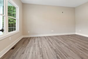 Empty room with light gray walls, large window, and wood-look flooring—ideal for new homes in Richmond VA.