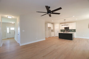 Open-plan living at Lot 81, Anderson Court, with light wood floors and a modern kitchen featuring a green backsplash.