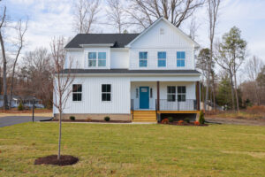 Two-story modern white house on Anderson Court with blue front door, front porch, and a small tree in the yard.