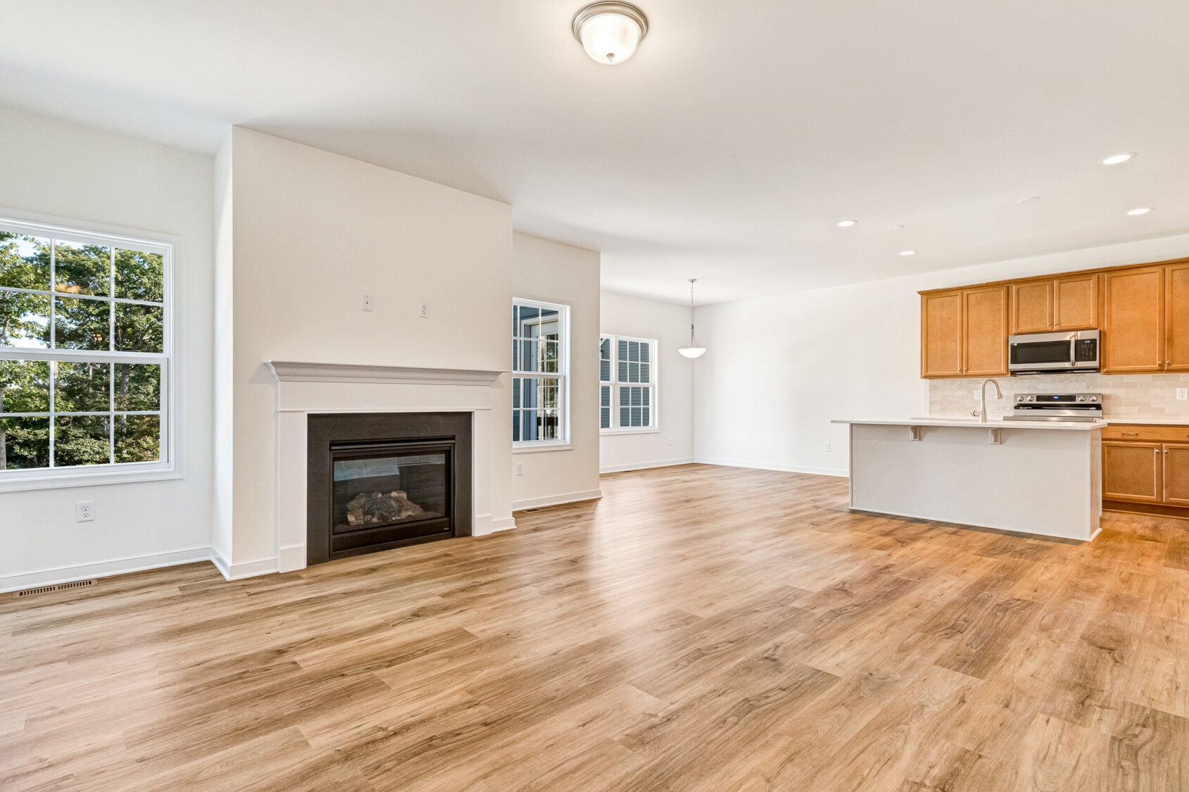 Open living area in Poplar Village, with wood floors, fireplace, large windows, and a sleek kitchen.