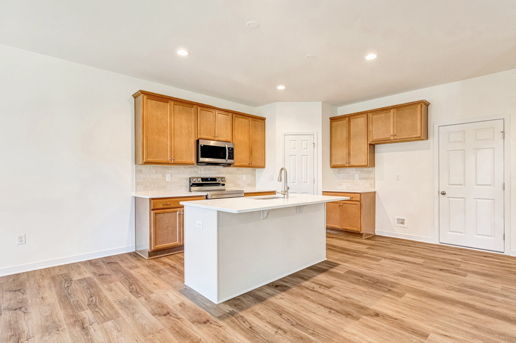 Modern kitchen in Poplar Village, Lot 29, with wood cabinets, white island, and stainless steel appliances.