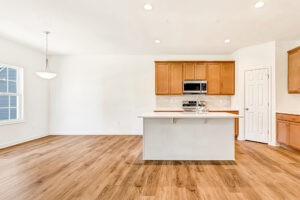 Bright, modern kitchen in Poplar Village with wood floors, center island, and dining area with large window.