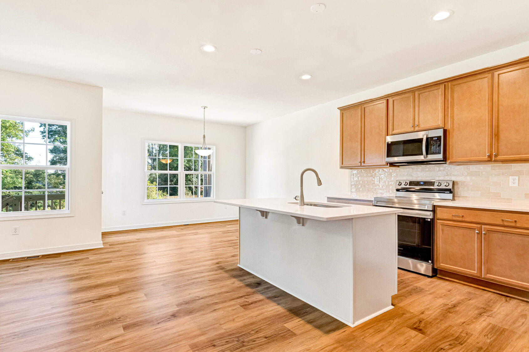 Bright modern kitchen in Poplar Village with wood floors, island, and stainless steel appliances.