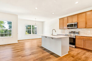 Bright modern kitchen in Poplar Village with wood floors, island, and stainless steel appliances.