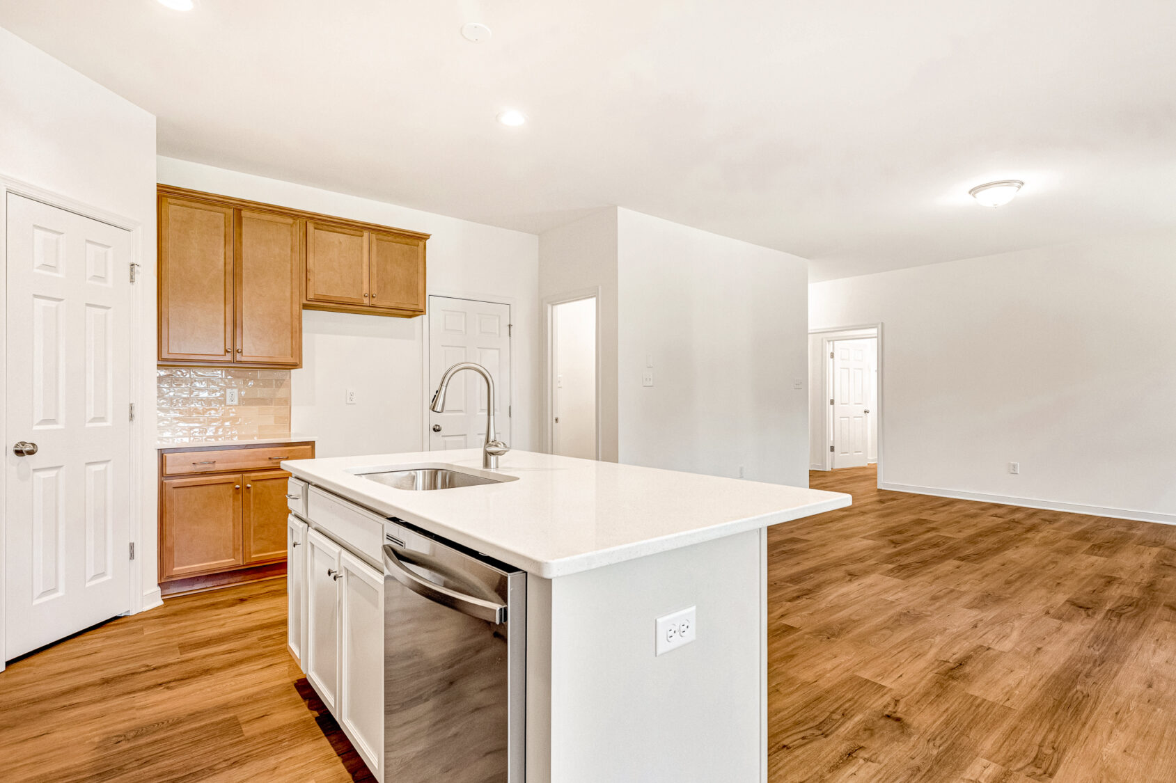 Modern kitchen in Poplar Village Lot 29 with wood floors, white island, and stainless steel dishwasher.
