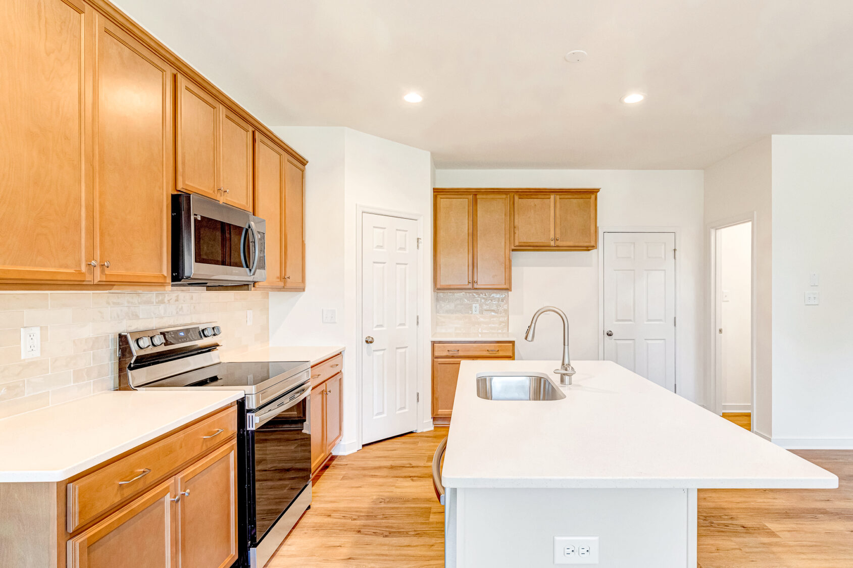 Modern kitchen in Poplar Village with wood cabinets, stainless appliances, and a white island with sink.