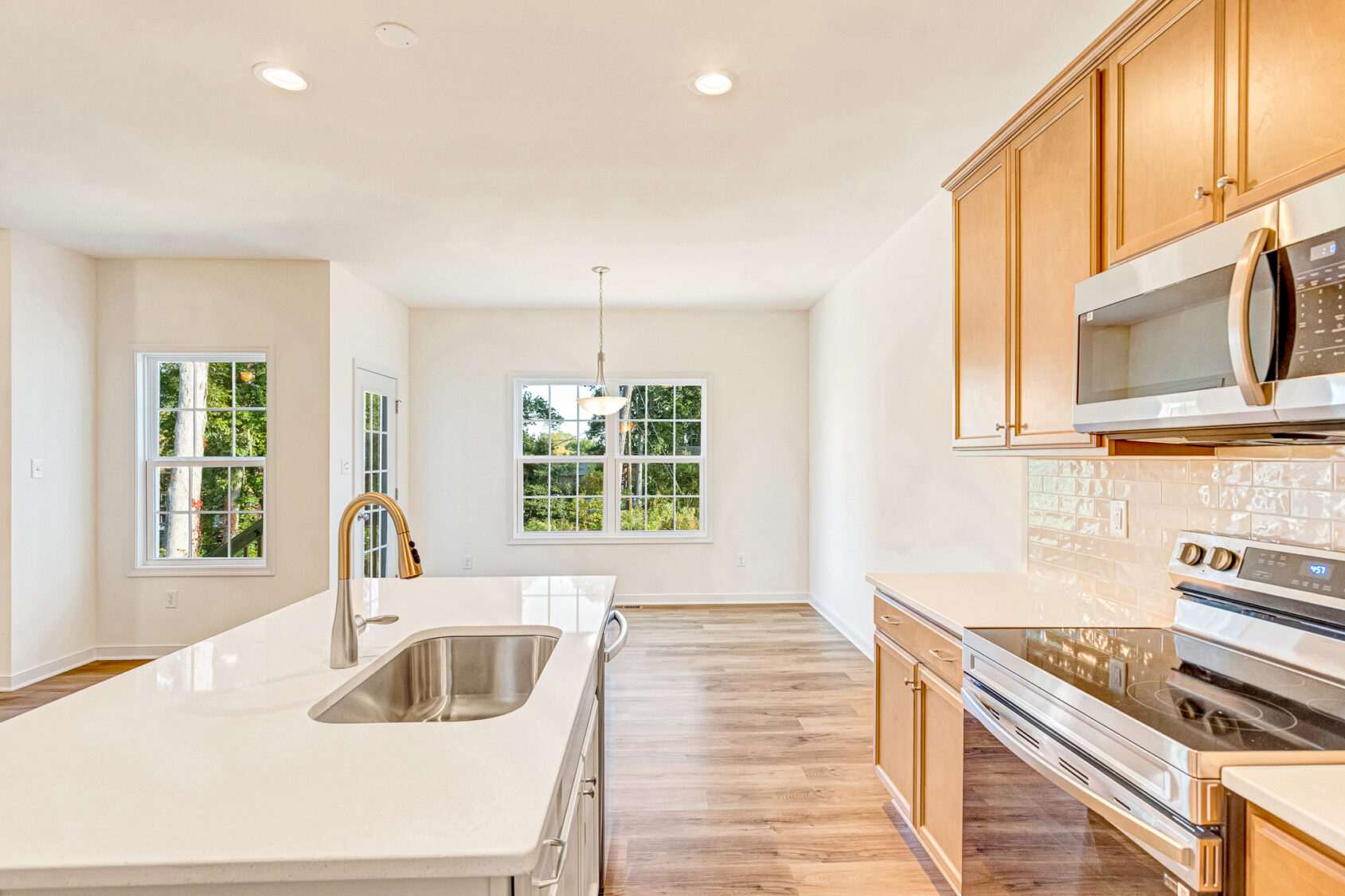 Bright modern kitchen in Poplar Village with wood cabinets, white countertops, and large windows letting in natural light.