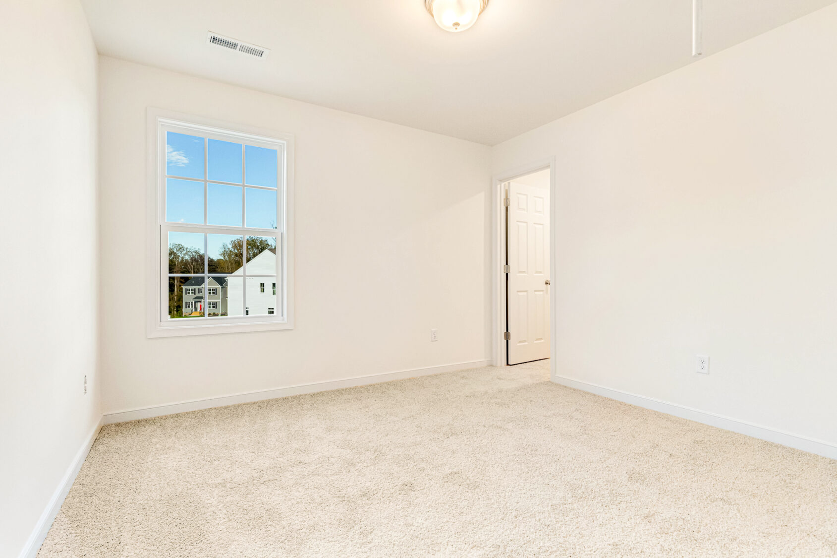Bright empty room in Poplar Village with beige carpet, white walls, window, and door to adjoining space.