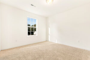 Bright empty room in Poplar Village with beige carpet, white walls, and a window letting in natural light.