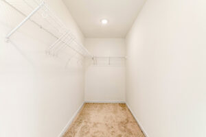 Empty walk-in closet in Lot 29, Poplar Village, with beige carpet, white walls, and white wire shelving on two sides.