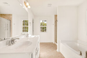 Bright Poplar Village bathroom with double sinks, bathtub, walk-in shower, and beige tiled floor in Lot 29.