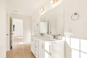 Bright bathroom with dual sinks, white cabinets, and large mirror in Poplar Village's Lot 29.