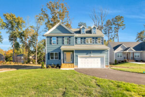 Two-story blue house with white trim and garage on sunny, grassy Lot 29 in Poplar Village.