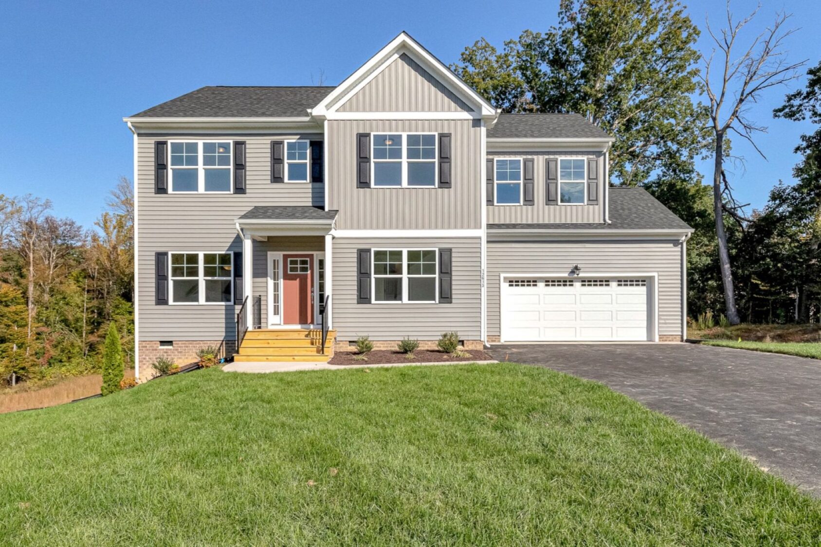 Two-story gray house with white trim in Poplar Village, front porch, garage, and green lawn on Lot 23.