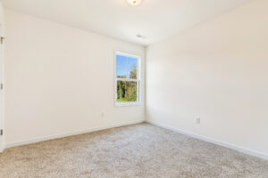 Empty room in Poplar Village, Lot 23, with beige carpet, white walls, and a window letting in natural light.