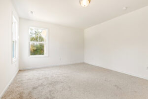 Empty room in Poplar Village, Lot 23, with beige carpet, white walls, ceiling light, and two bright windows.