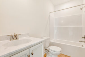 Bright, clean bathroom in Lot 23, Poplar Village, with white vanity, marble countertop, toilet, and tub-shower combo.