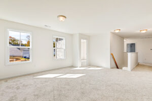 Bright, carpeted upstairs room in Poplar Village Lot 23 with windows, white walls, and abundant natural light.