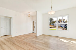 Bright, empty room in Poplar Village's Lot 23 with light wood floors, white walls, and large window.