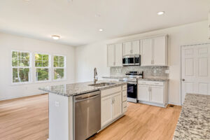 Modern kitchen in Poplar Village with white cabinets, granite countertops, stainless appliances, and large windows.