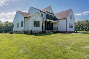 Modern white house with dark trim in Hanover’s Shirley Commons, large windows, and a spacious green lawn on a sunny day.