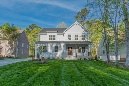 Charming white two-story house in Shirley Commons, offering senior living in Stafford with a sunny porch and neat lawn.