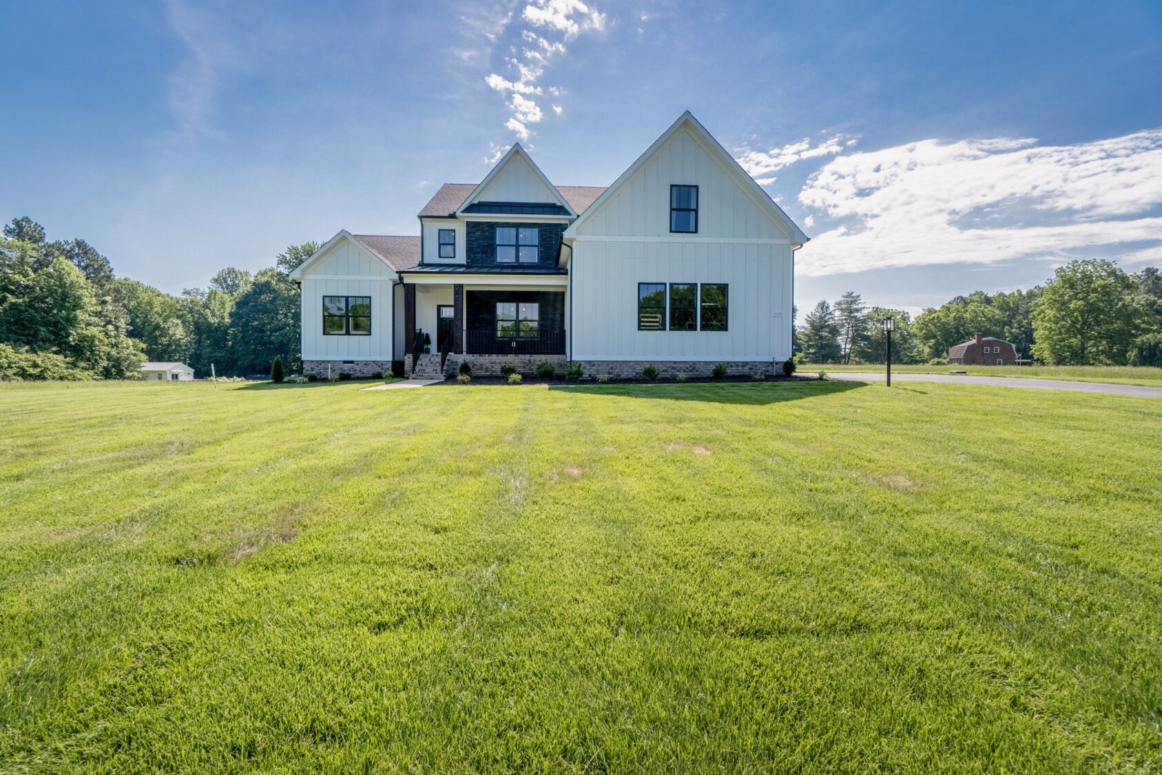 Modern farmhouse Hanover apartment with white siding, black accents, and large windows under a sunny sky.