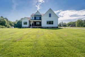 Modern farmhouse Hanover apartment with white siding, black accents, and large windows under a sunny sky.