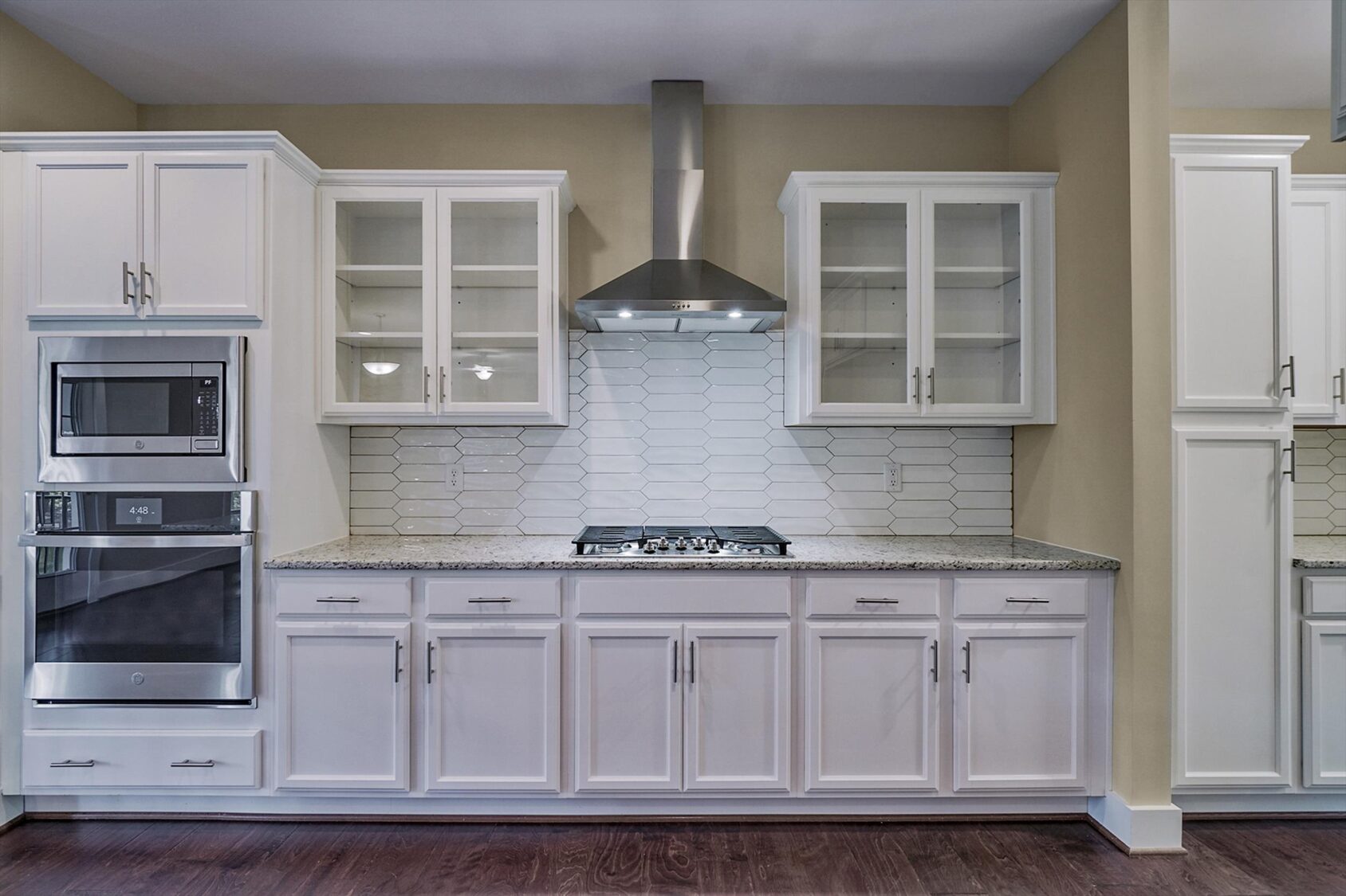 Modern Poplar Village kitchen with white cabinets, stainless steel appliances, and hexagon tile backsplash.