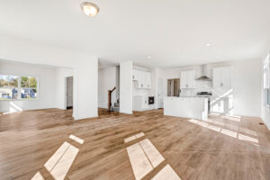 Bright, modern open-concept kitchen and living area in Poplar Village Lot 13 with wood floors and sunny windows.