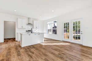 Bright modern kitchen in Poplar Village with white cabinets, island, wood floors, and large sunlit windows.