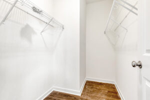 Empty walk-in closet with white wire shelves, white walls, and wooden floor in Poplar Village's Lot 13.