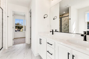 Bright modern bathroom with double sinks, black fixtures, and large mirror in Poplar Village Lot 13.