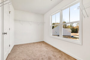 Bright, empty walk-in closet in Lot 13, Poplar Village with beige carpet, white walls, and large window.