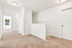 Bright hallway in Poplar Village with beige carpet, white walls, and natural light; doors lead to other rooms.