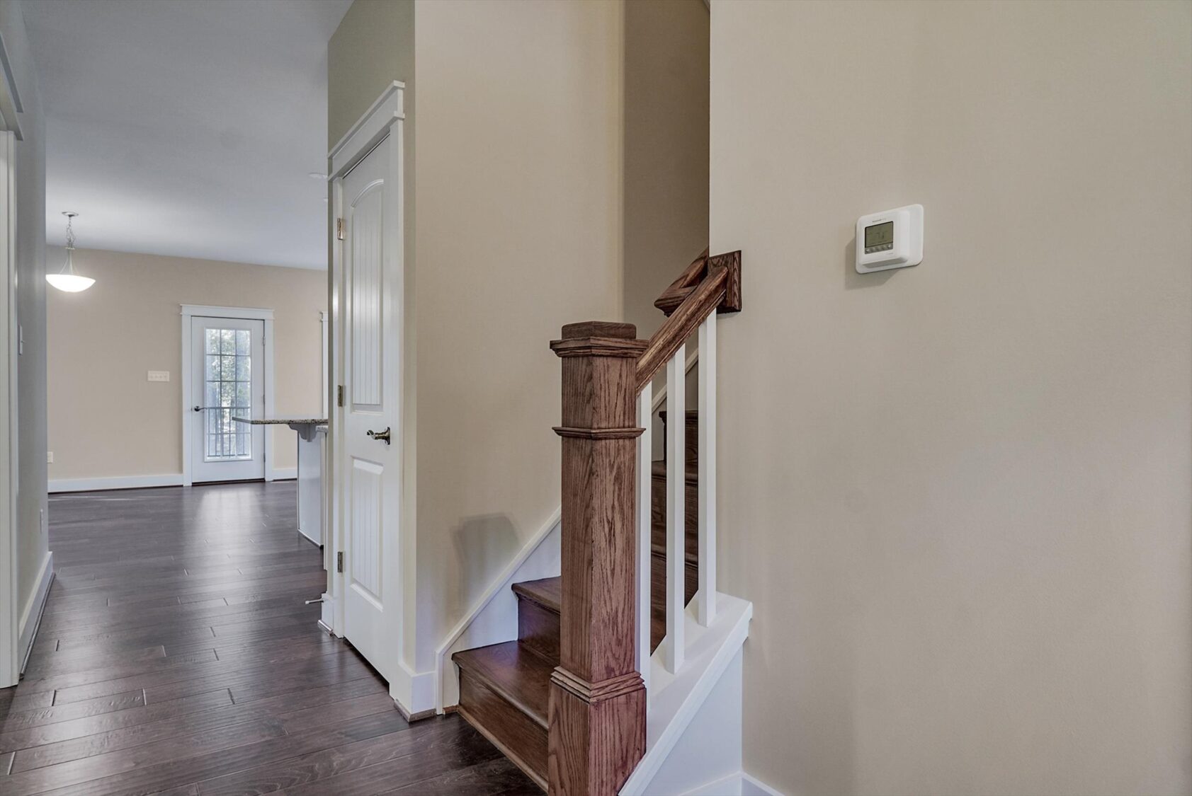 Wooden stairs with a white railing in Albany's Poplar Village, leading up from a hallway with dark wood flooring.