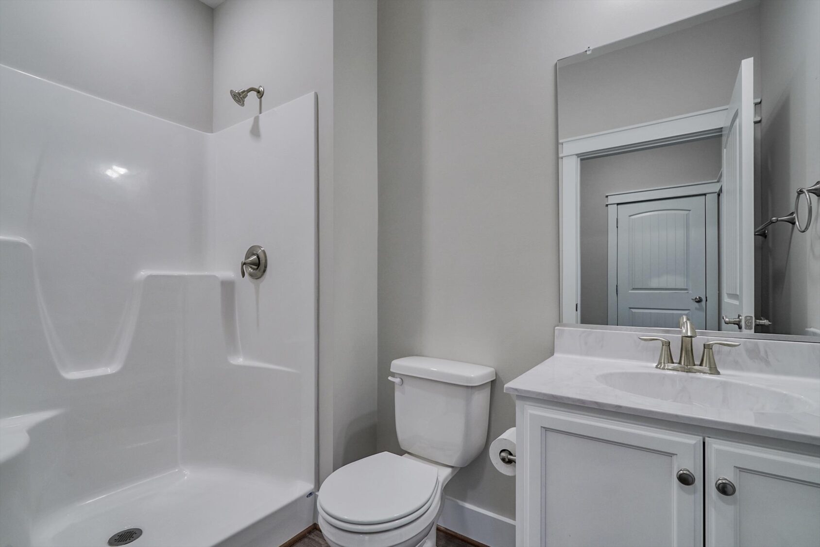 Modern bathroom in Poplar Village, Albany, with a white shower, toilet, sink, gray walls, and a large mirror.