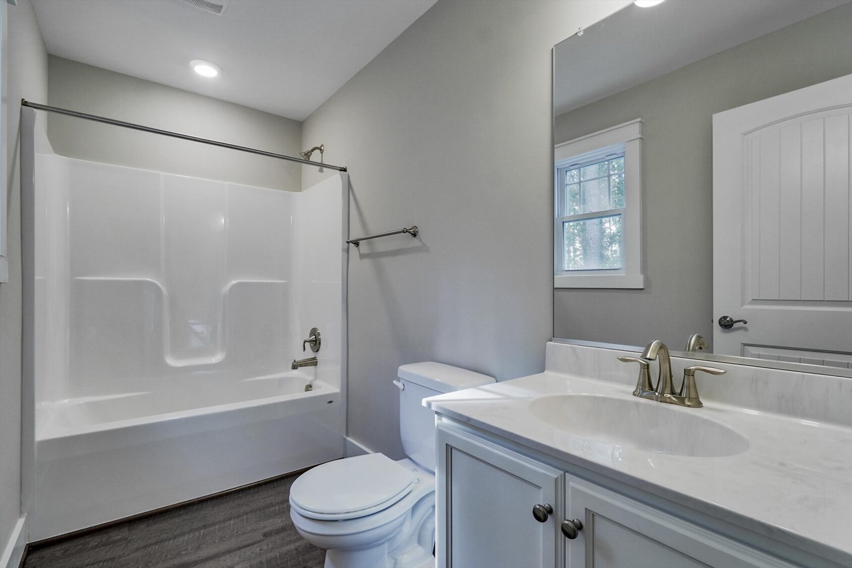 Modern Poplar Village bathroom with a white tub-shower, marble sink, and light gray walls in Albany.