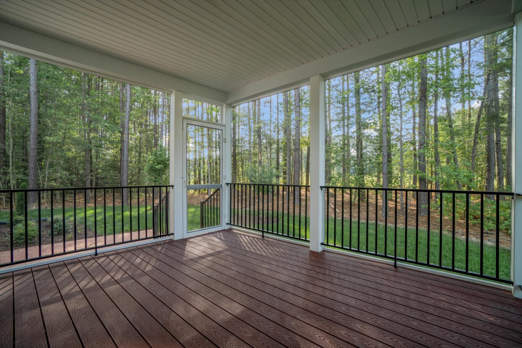 Screened-in porch with wooden floor, black railings, and views of trees in Poplar Village, Albany.