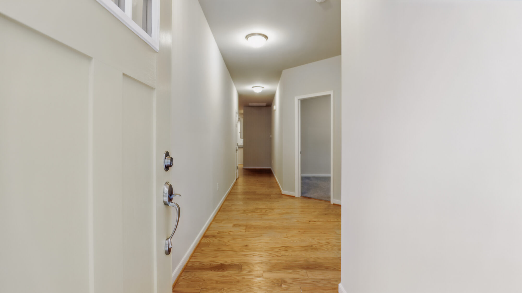 A hallway with wooden floors, white walls, and ceiling lights in a serene Somerset Hill or Bethany home.