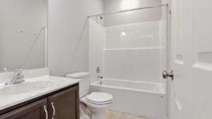 Clean, modern bathroom at Somerset Hill with a white bathtub, dark wood vanity, and large mirror.