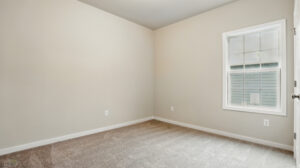 Empty room in Somerset Hill with beige walls, gray carpet, single window, and white trim.