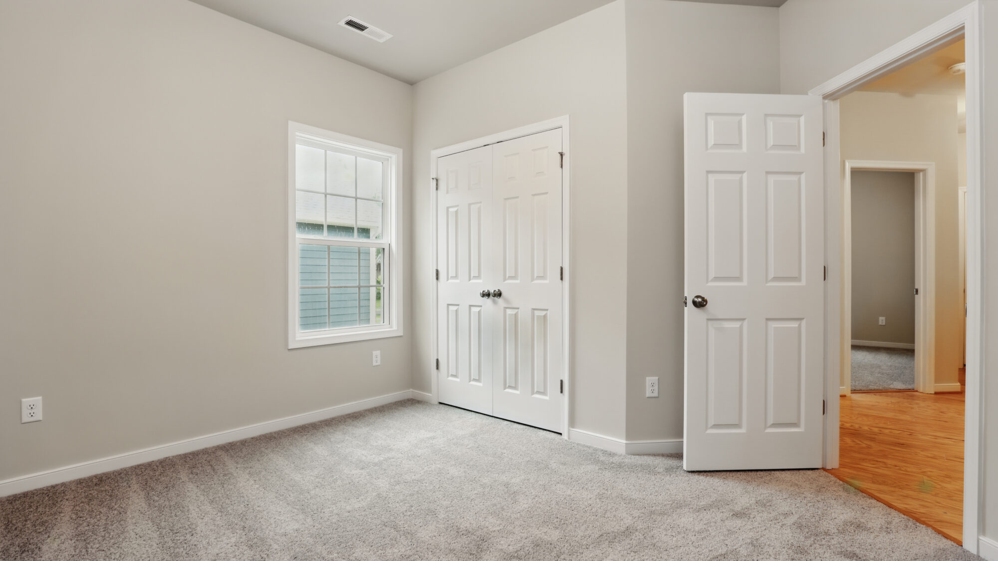 Empty room in Somerset Hill with beige carpet, white walls, closet, open door, and natural light from window.
