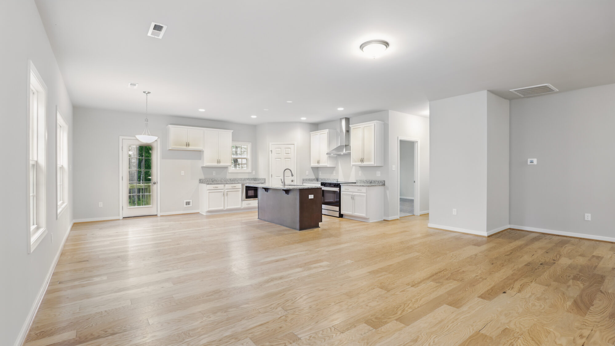 Spacious modern Somerset Hill kitchen with white cabinets, center island, wood floors, and large windows in open-plan layout.