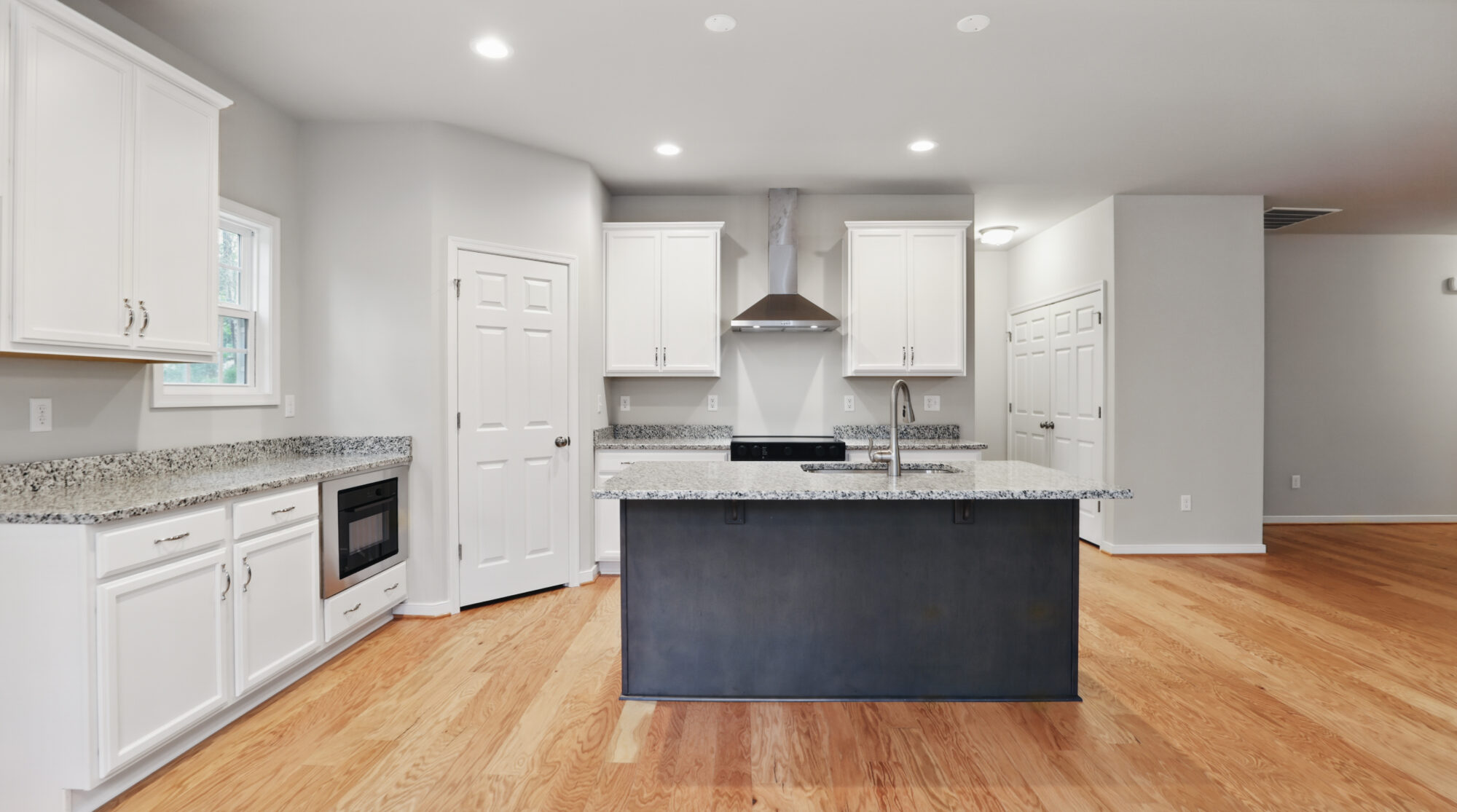 Modern Bethany kitchen with white cabinets, granite countertops, island, and stainless steel appliances.