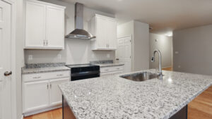 Modern Somerset Hill kitchen with white cabinets, stainless appliances, and a granite island with a sink.