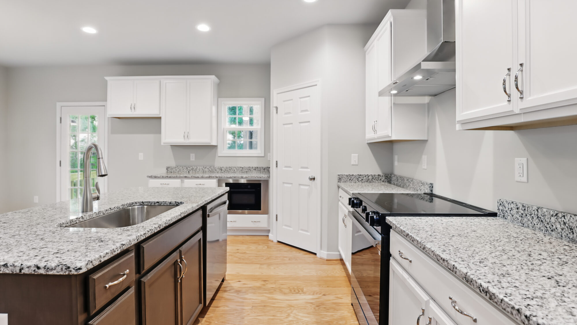 Modern Bethany kitchen with granite countertops, white cabinets, stainless appliances, and wood flooring.