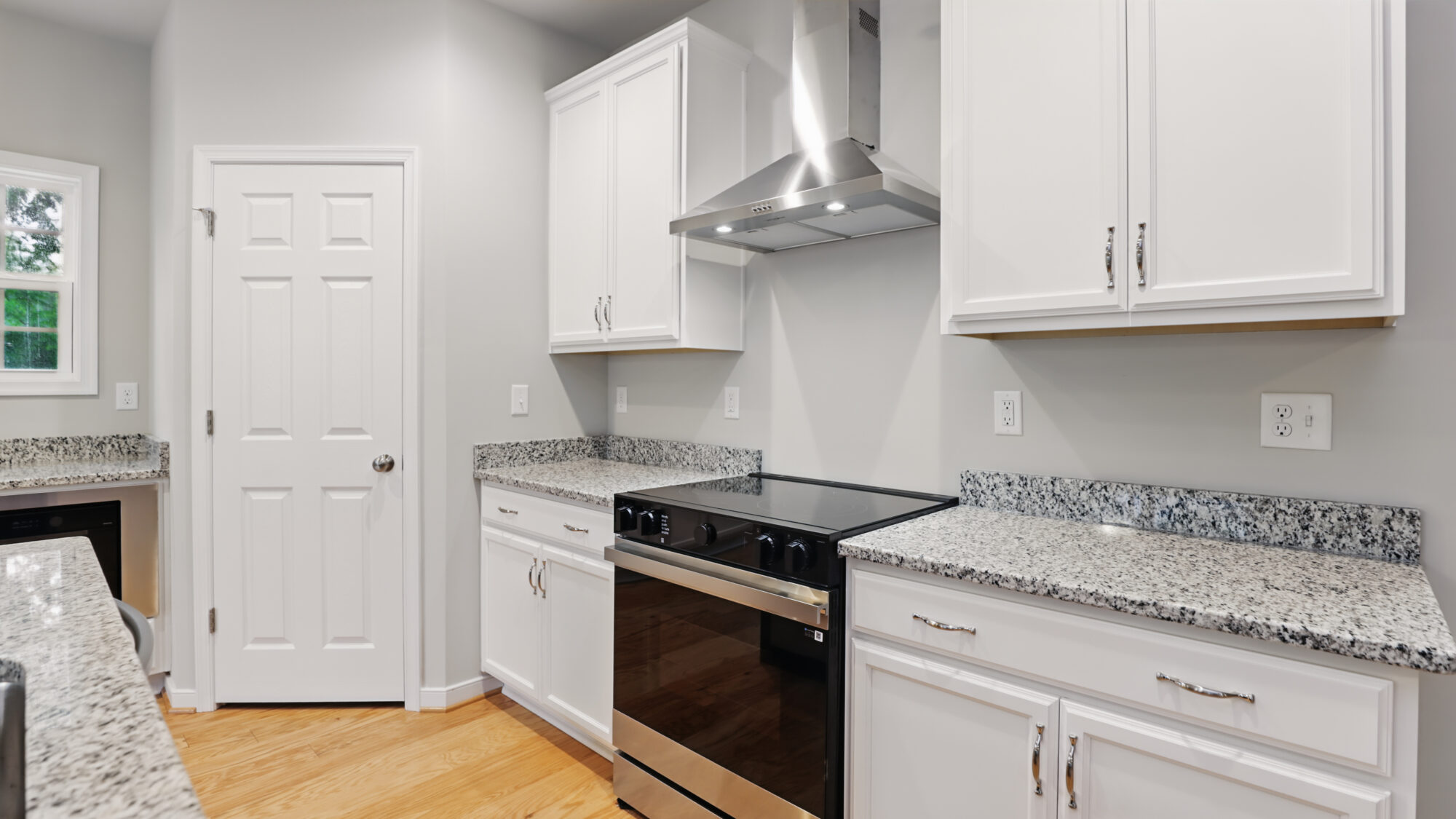 Modern Somerset Hill kitchen with white cabinets, stainless steel stove, granite countertops, and wood flooring.