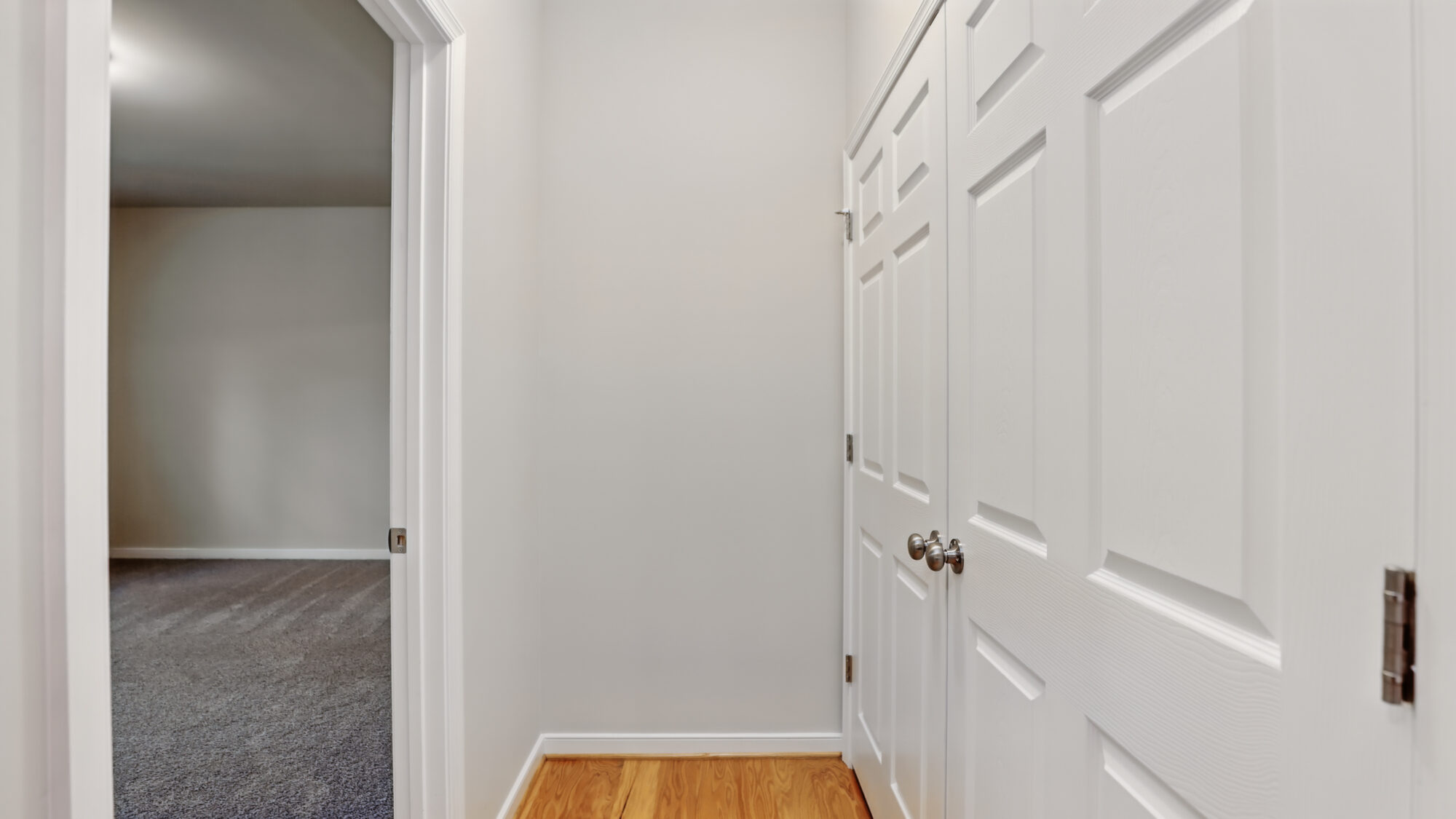 Bright hallway with wood flooring at Somerset Hill, white doors, and a carpeted Bethany room on the left.