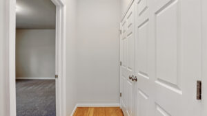 Bright hallway with wood flooring at Somerset Hill, white doors, and a carpeted Bethany room on the left.